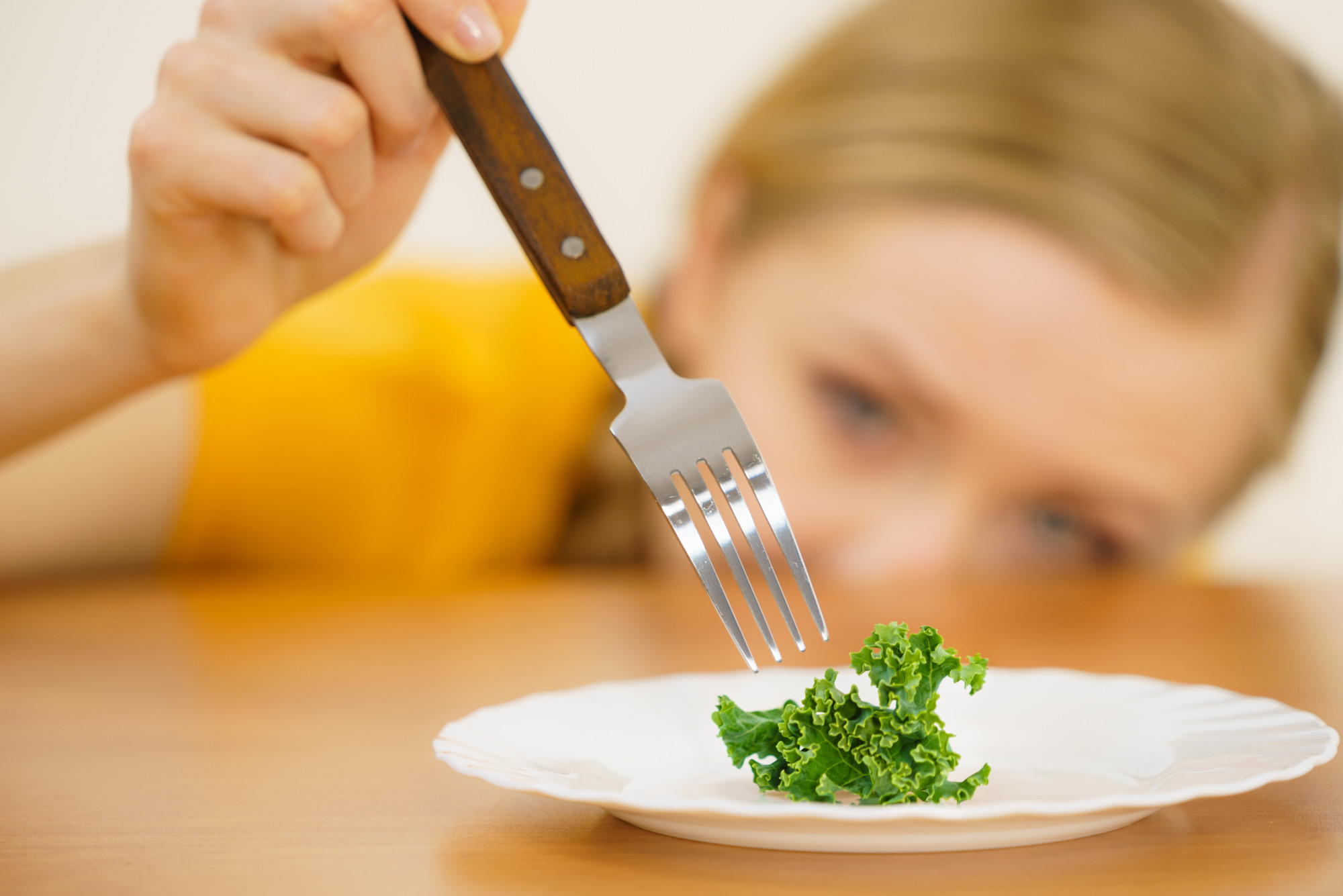 person eating single piece of lettuce on plate