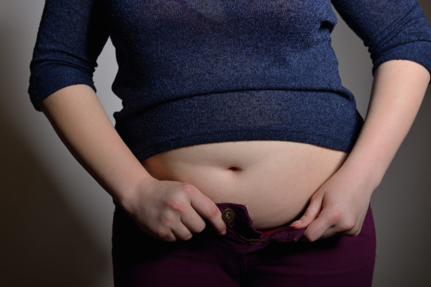 woman trying to button pants over chubby gut